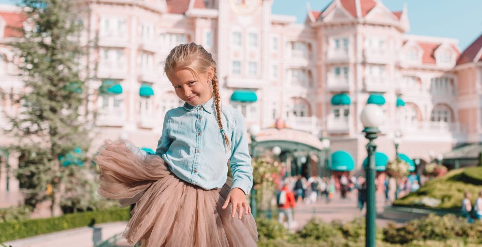 Little adorable girl in Cinderella dress at fairy-tale Disneyland park Little adorable girl outdoor in the park