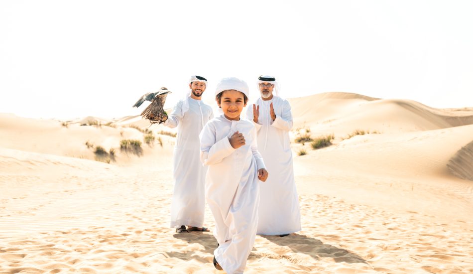 Three generation family making a safari in the desert of Dubai Three generation family making a safari in the desert of Dubai. Grandfather, son and grandson spending time together in the nature and training their falcon bird.