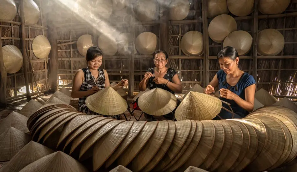 Group of Vietnamese female craftsman making the traditional viet Group of Vietnamese female craftsman making the traditional vietnam hat in the old traditional house in Ap Thoi Phuoc village, Hochiminh city, Vietnam, traditional artist concept