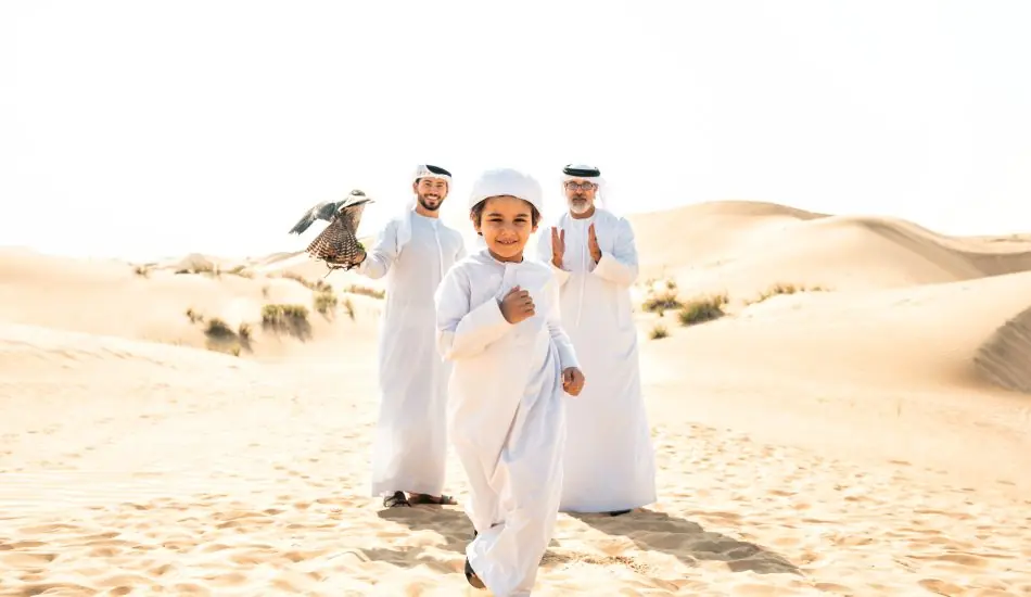 Three generation family making a safari in the desert of Dubai Three generation family making a safari in the desert of Dubai. Grandfather, son and grandson spending time together in the nature and training their falcon bird.